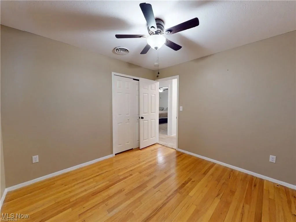 Unfurnished bedroom with light wood-type flooring, a ceiling fan, and a closet