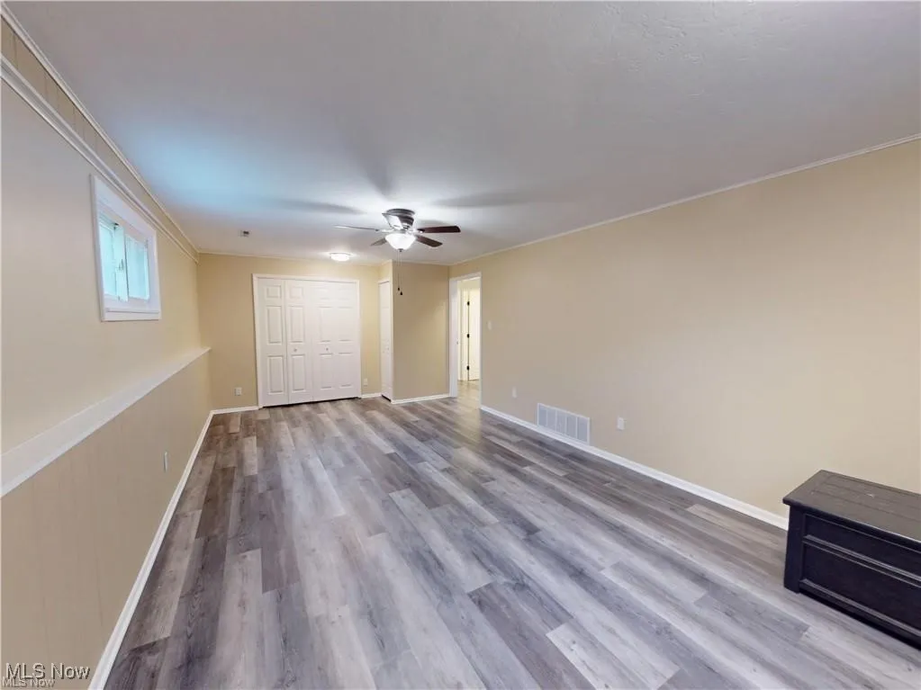 Unfurnished bedroom featuring light wood finished floors, a closet, ceiling fan, and ornamental molding