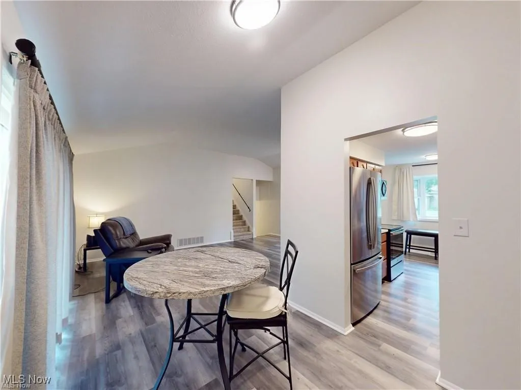 Dining space featuring light wood-style flooring, stairs, and lofted ceiling