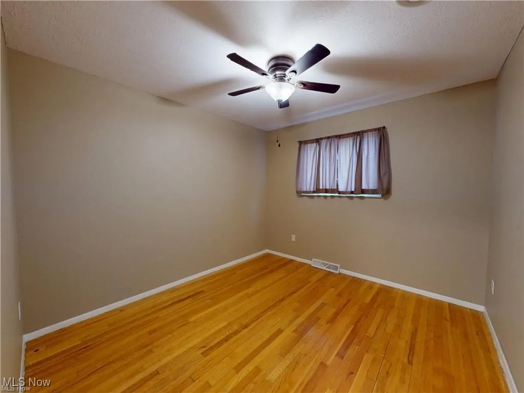 Unfurnished room featuring light wood-style floors, a ceiling fan, and a textured ceiling