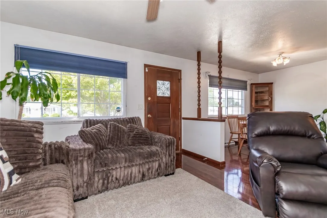 Living area with a textured ceiling, wood finished floors, and a ceiling fan