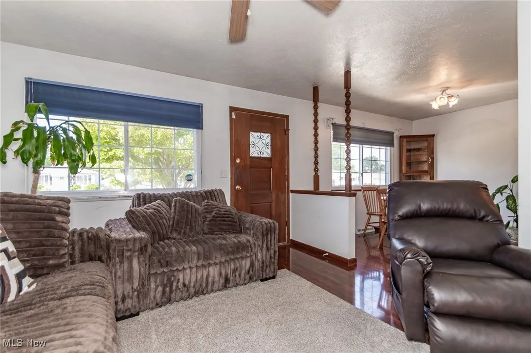 Living area with a textured ceiling, dark wood finished floors, and a ceiling fan