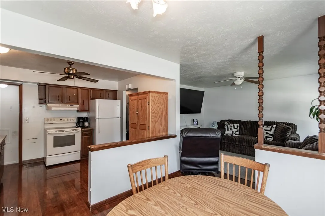 Dining space featuring ceiling fan, dark wood-type flooring, and a textured ceiling