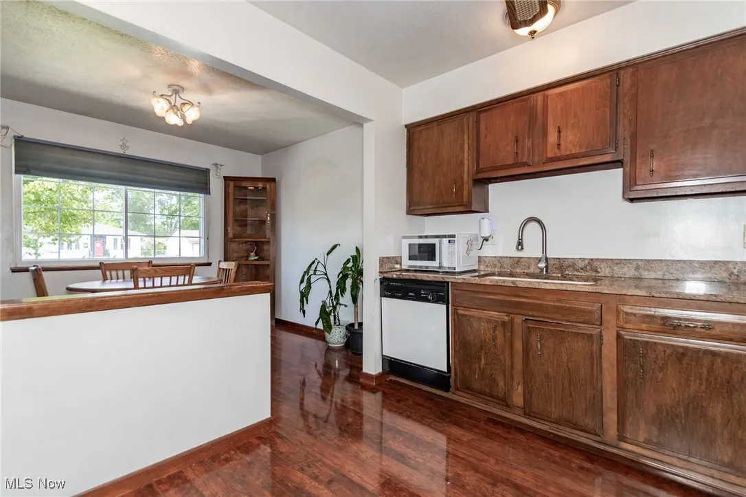 Kitchen featuring white appliances, dark wood finished floors, and light stone counters