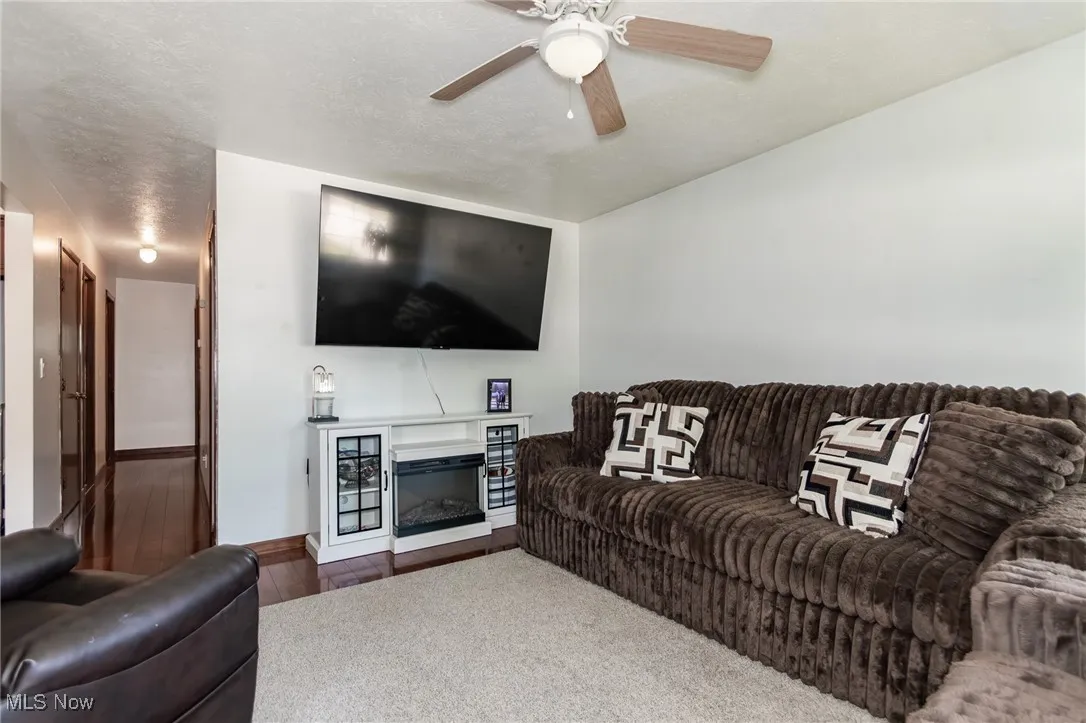 Living area featuring a textured ceiling, wood finished floors, and a ceiling fan