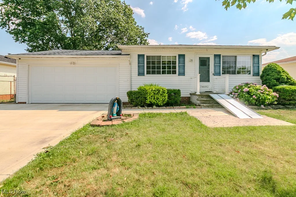 Ranch-style home featuring concrete driveway, a garage, and a front lawn