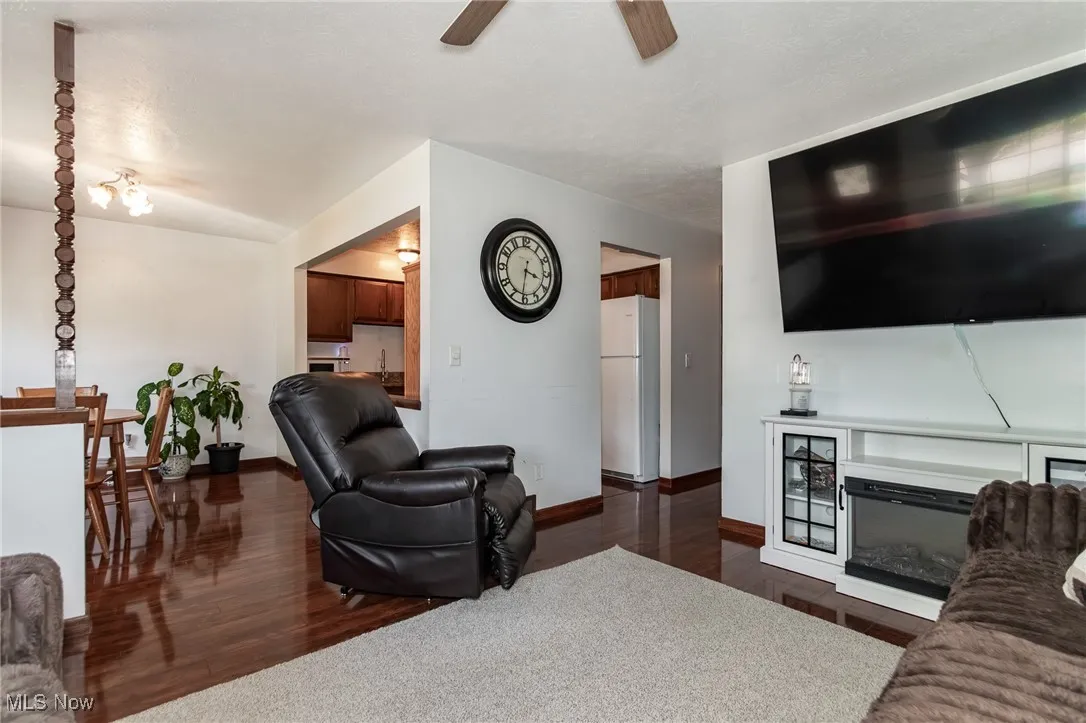 Living area with dark wood-style flooring and a glass covered fireplace