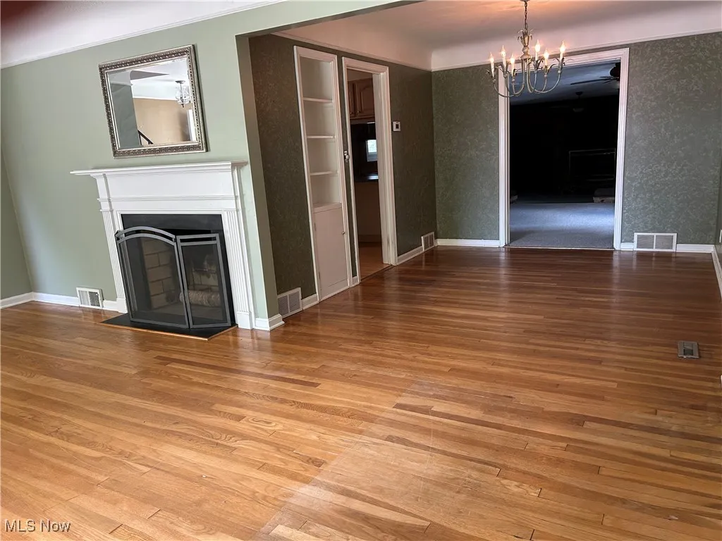 Unfurnished living room with hardwood / wood-style floors, a fireplace, and a chandelier