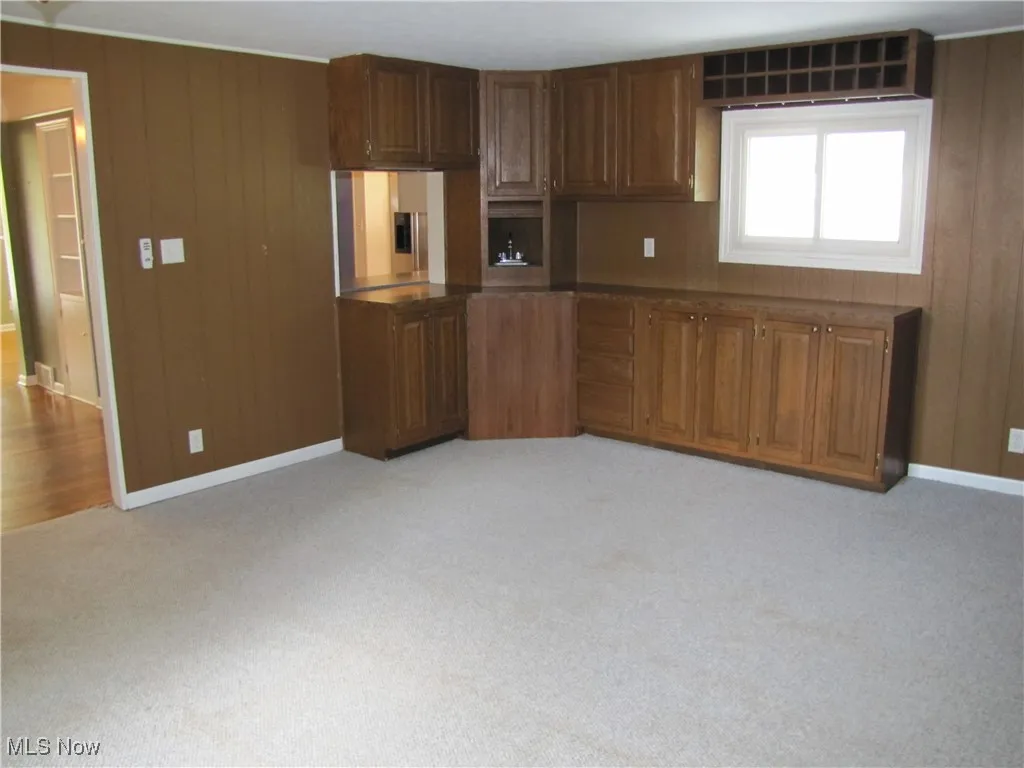 Kitchen with wooden walls, dark countertops, and light carpet