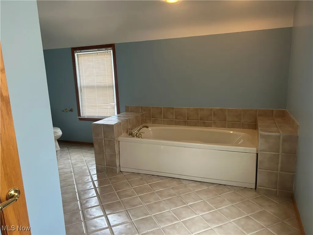 Bathroom with light tile patterned floors and a garden tub