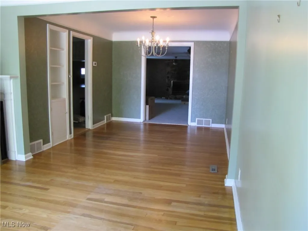 Unfurnished dining area with a chandelier and light wood-style floors