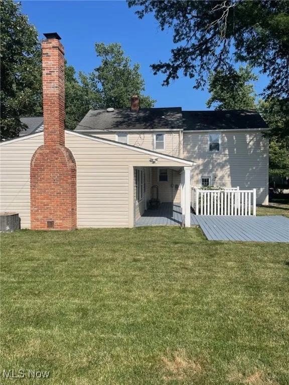 Back of house with a yard, a wooden deck, and a chimney