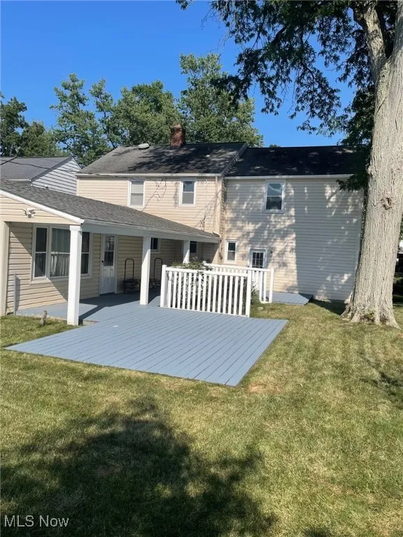 Back of house with a wooden deck, a lawn, and a chimney