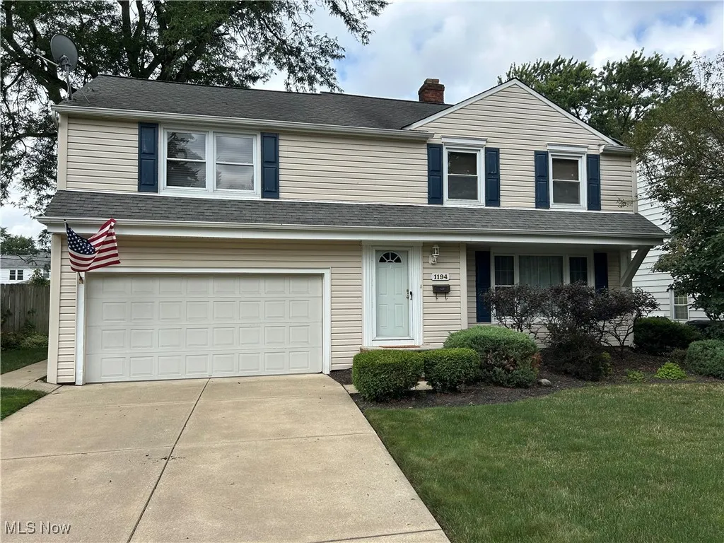 Traditional-style house with a garage, concrete driveway, a front lawn, a porch, and a chimney