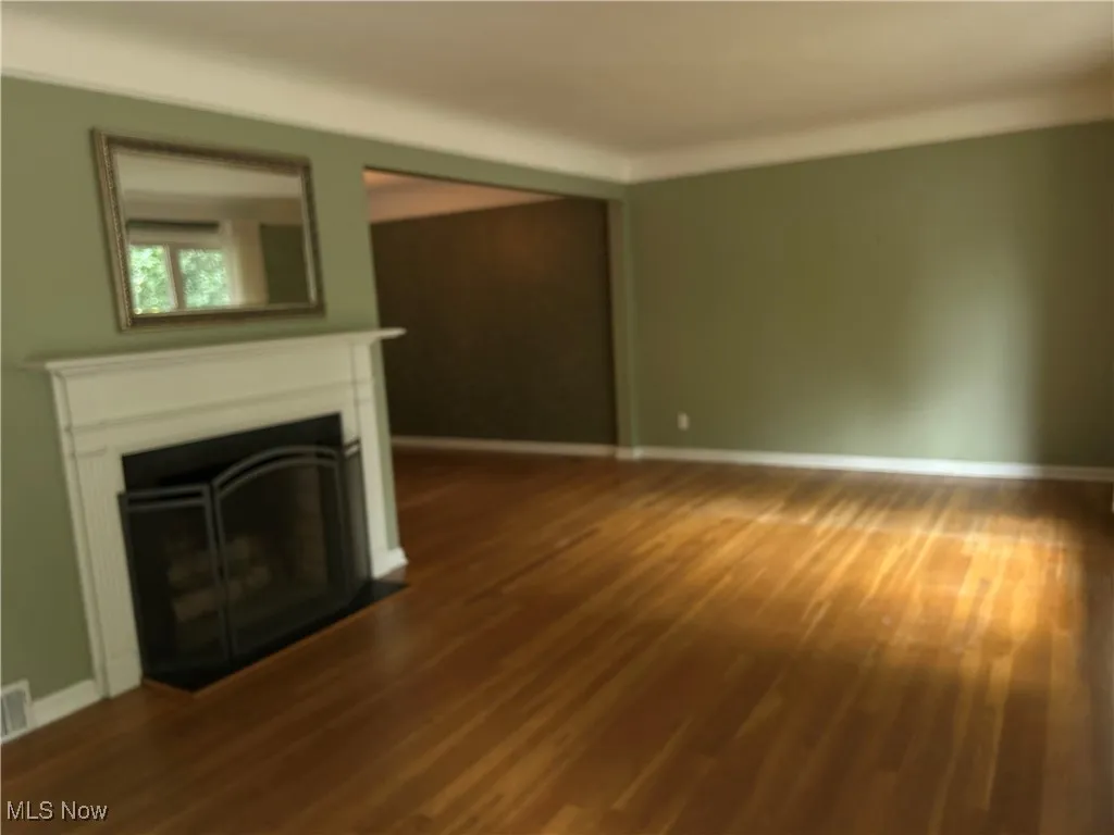 Unfurnished living room with a fireplace with flush hearth and dark wood-style flooring