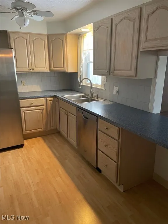 Kitchen featuring light wood-style flooring, appliances with stainless steel finishes, light brown cabinets, and a textured ceiling