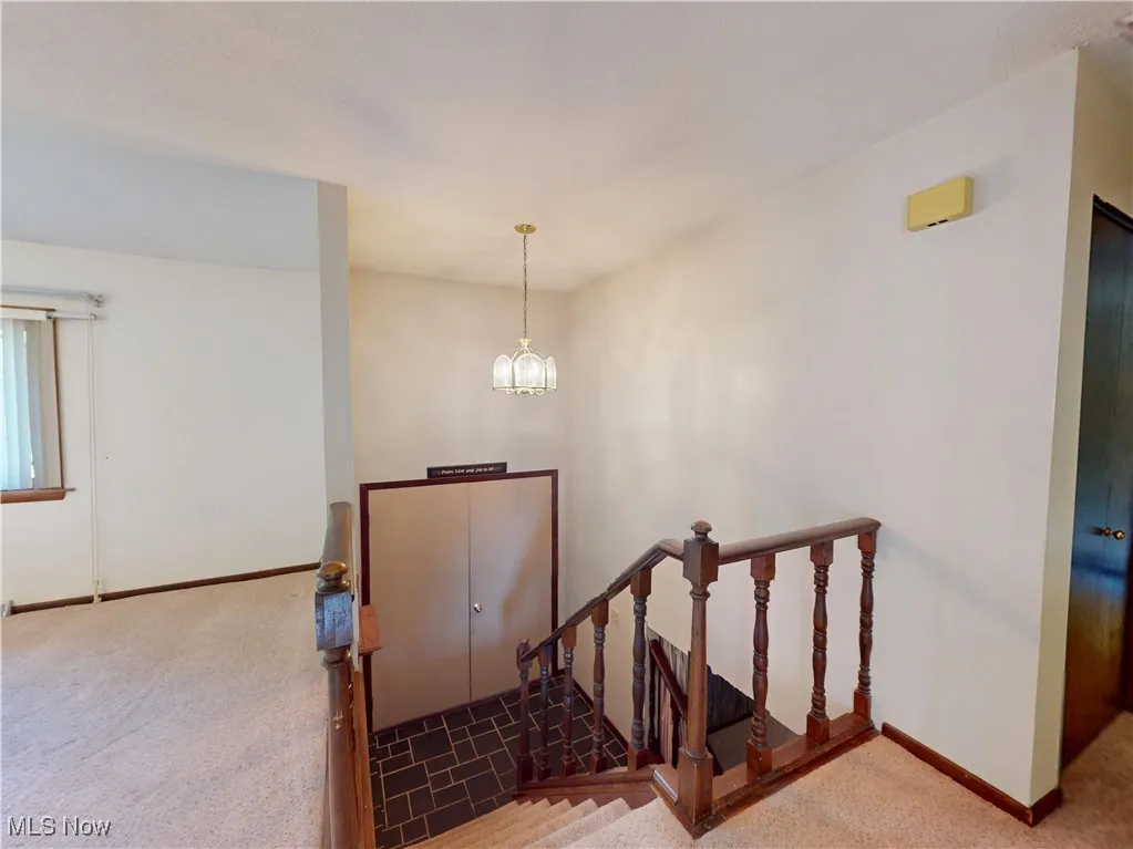 Staircase featuring carpet flooring and a chandelier