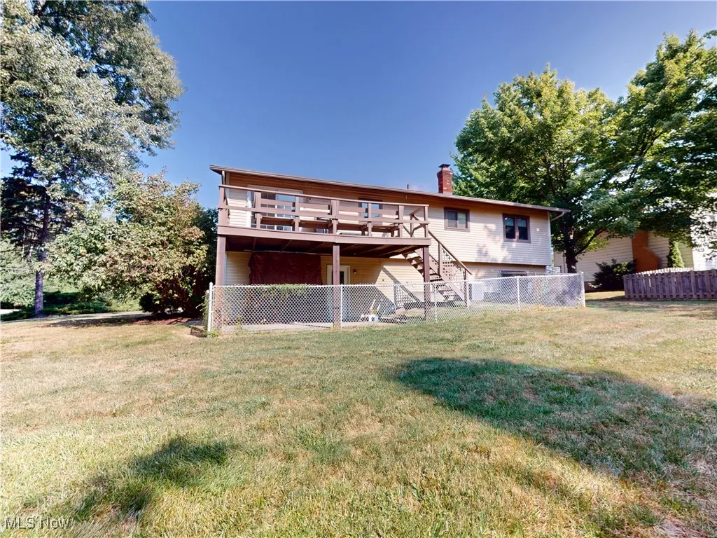 Back of property featuring stairs, a chimney, and a deck