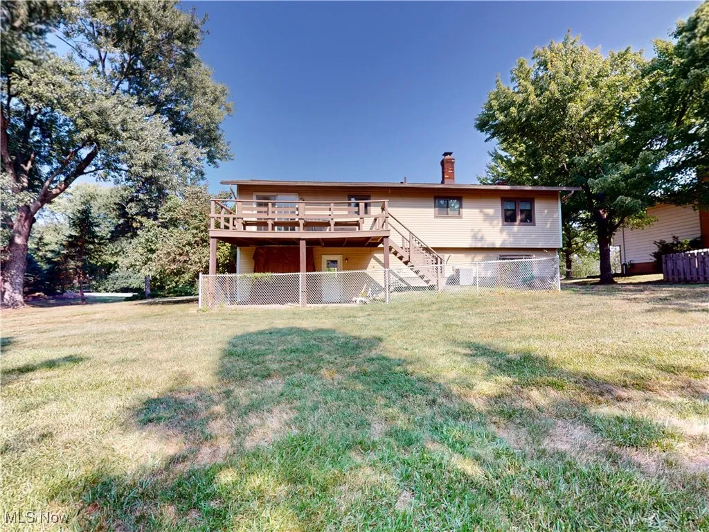 Back of house featuring stairs, a chimney, and a deck