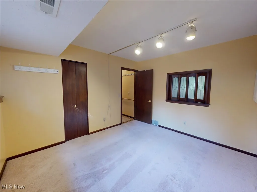Unfurnished bedroom featuring a closet, track lighting, and carpet