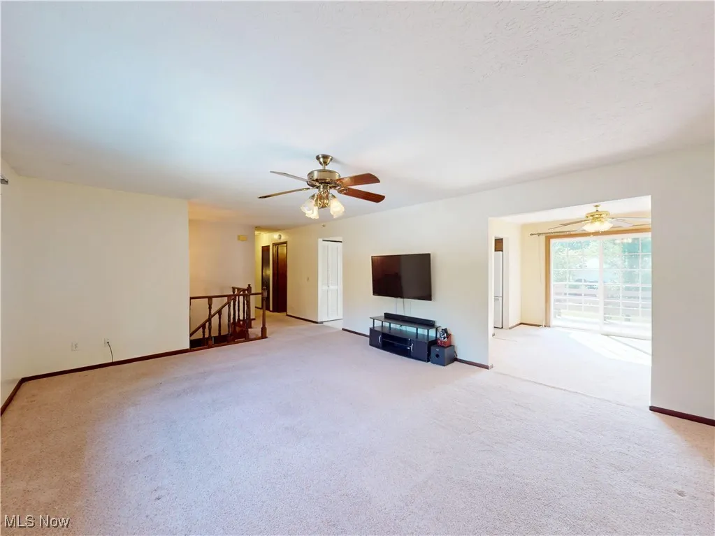 Unfurnished living room with carpet and ceiling fan