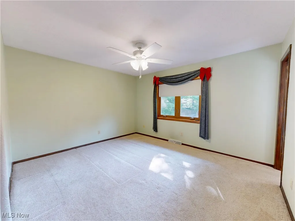 Carpeted empty room featuring baseboards and ceiling fan