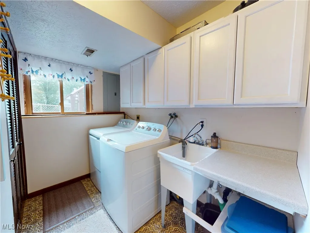Washroom featuring a textured ceiling, washer and dryer, and cabinet space