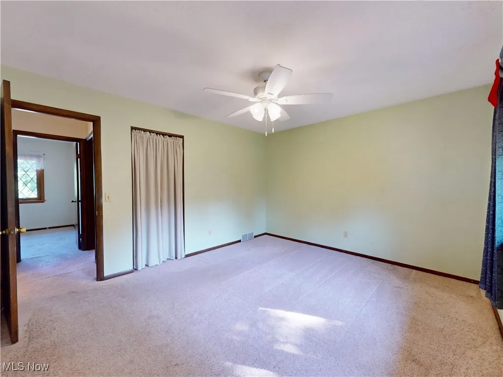 Unfurnished bedroom with light colored carpet and a ceiling fan