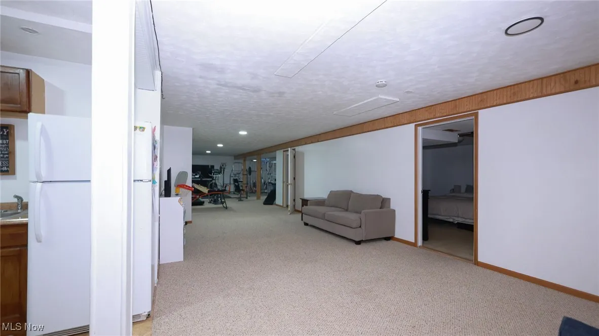 Hallway with light colored carpet and a textured ceiling