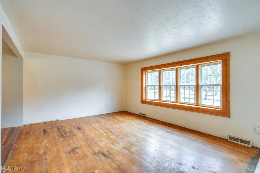 Unfurnished room featuring hardwood  floors and a textured ceiling