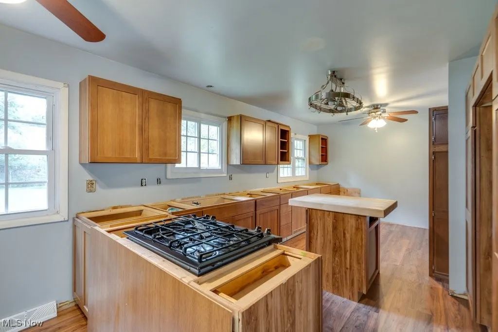 Kitchen with a ceiling fan, light wood-style flooring, a center island, and open shelves