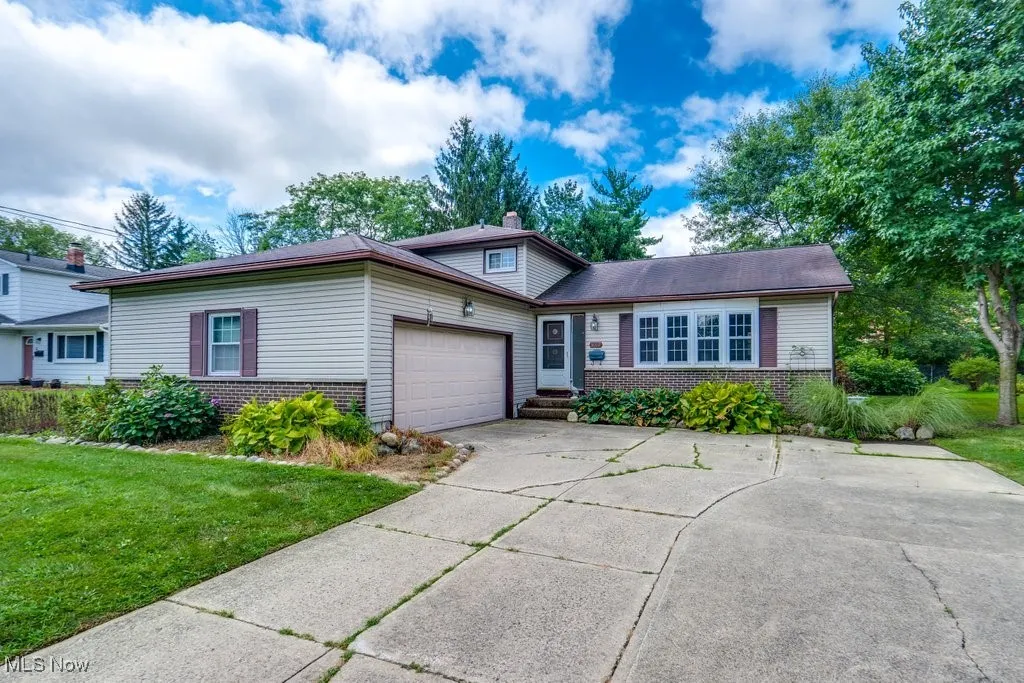 View of front of house featuring brick siding, an attached garage, concrete driveway, a chimney, and a front yard