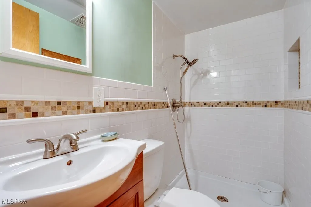 Full bathroom featuring vanity, a shower stall, and tile walls