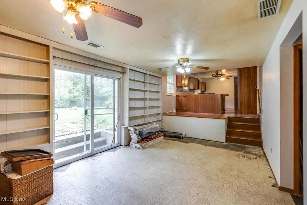 Unfurnished living room with a ceiling fan, stairway, light floors, and built in features