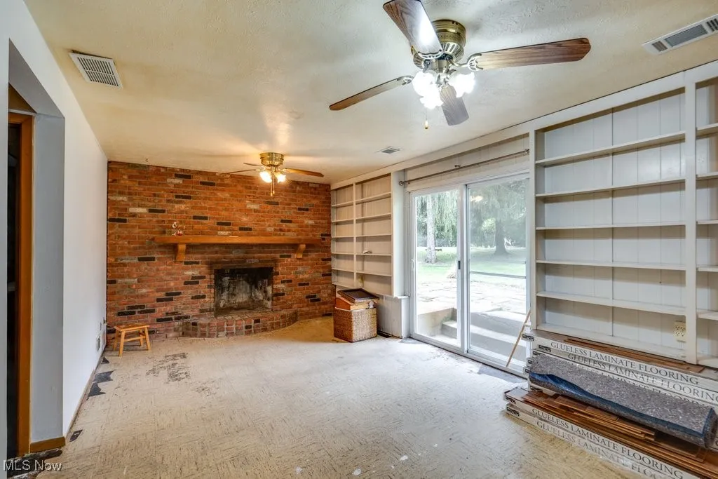 Unfurnished living room with a brick fireplace, a textured ceiling, and built in features