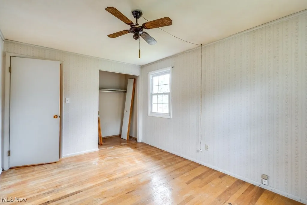 Unfurnished bedroom featuring wood finished floors, a closet, and ceiling fan