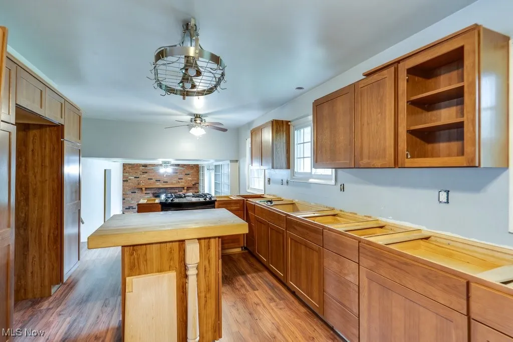 Kitchen with light wood finished floors, open shelves, a kitchen island with butcher block counter, and cabinets (need countertops)