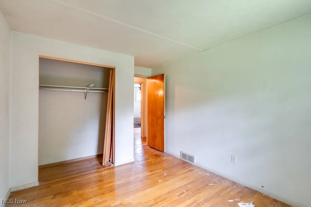 Unfurnished bedroom with wood finished floors and a closet