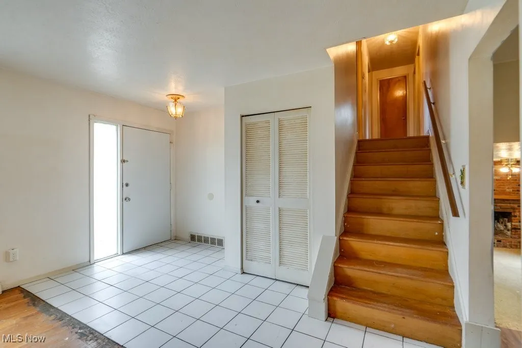 Entrance foyer with light tile patterned floors and stairway