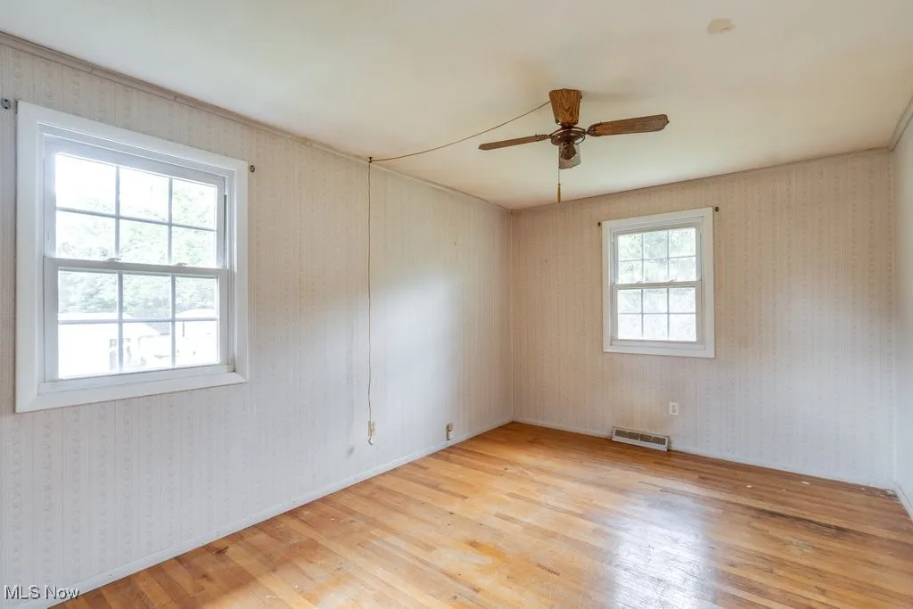 Unfurnished bedroom with light wood-type flooring, wallpapered walls, and ceiling fan