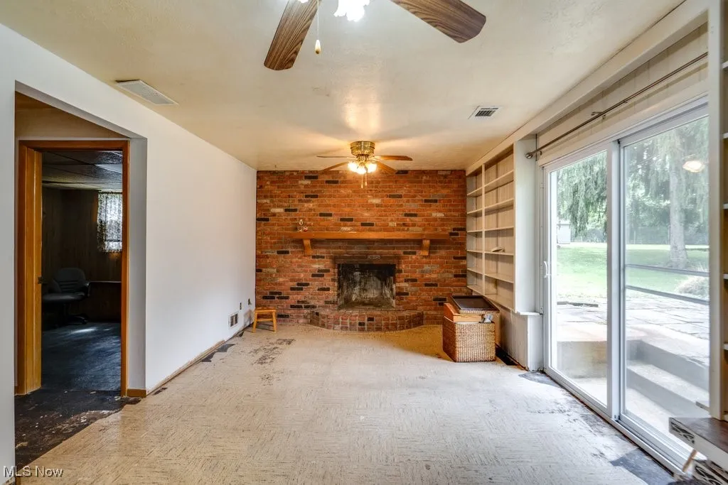 Unfurnished living room featuring a fireplace, built in features, and carpet
