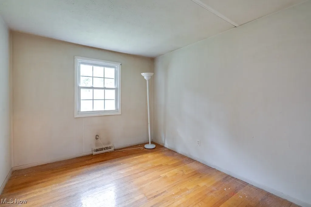 Spare room featuring hardwood / wood-style flooring and baseboards