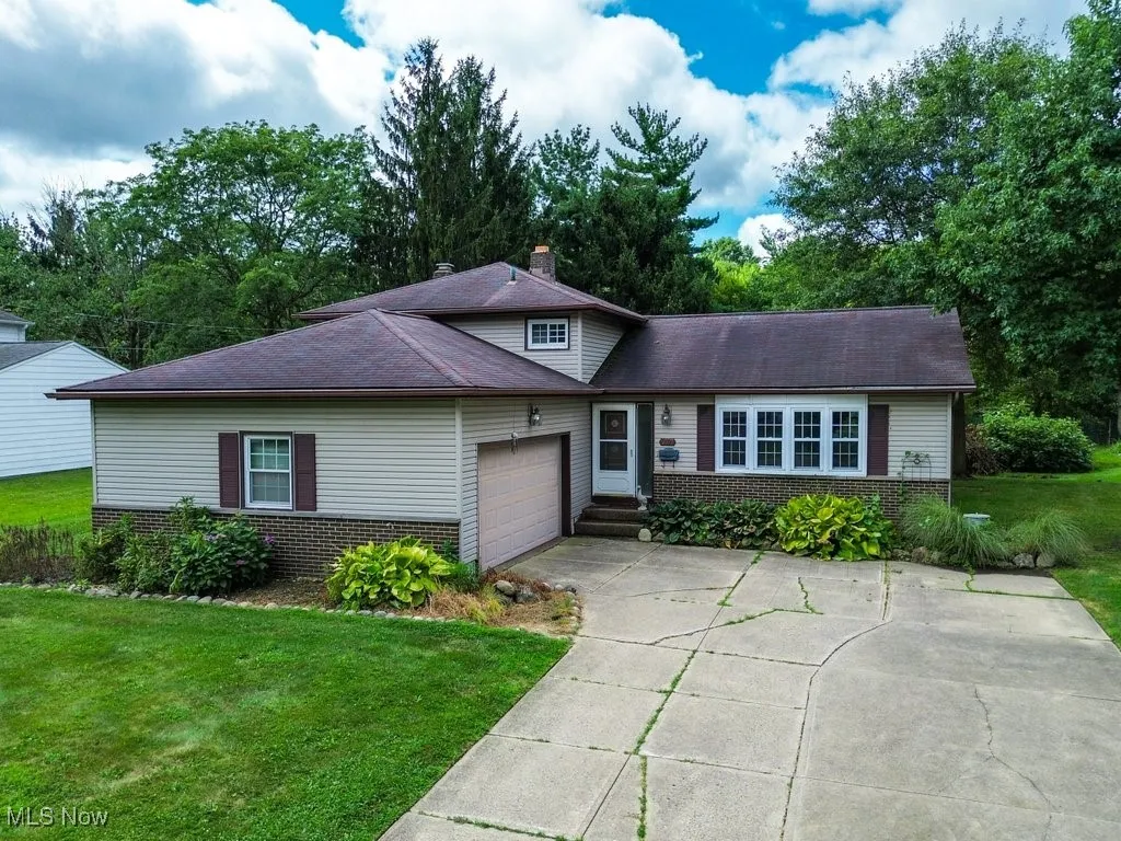 View of front of house featuring brick siding, an attached garage, a front lawn, driveway, and a chimney