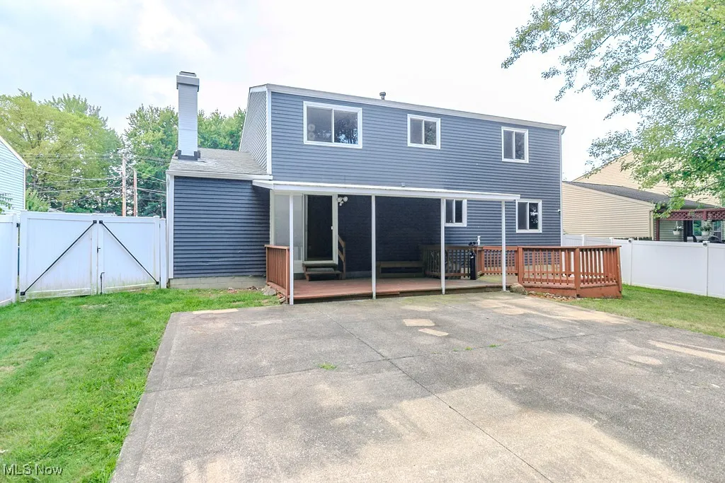 Back of house featuring a gate, a wooden deck, and a chimney