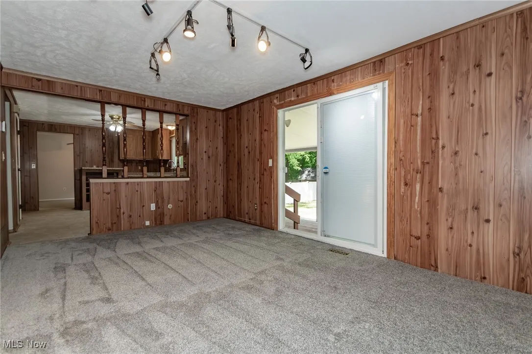 Family room with wooden walls, light carpet, and sliding glass doors.