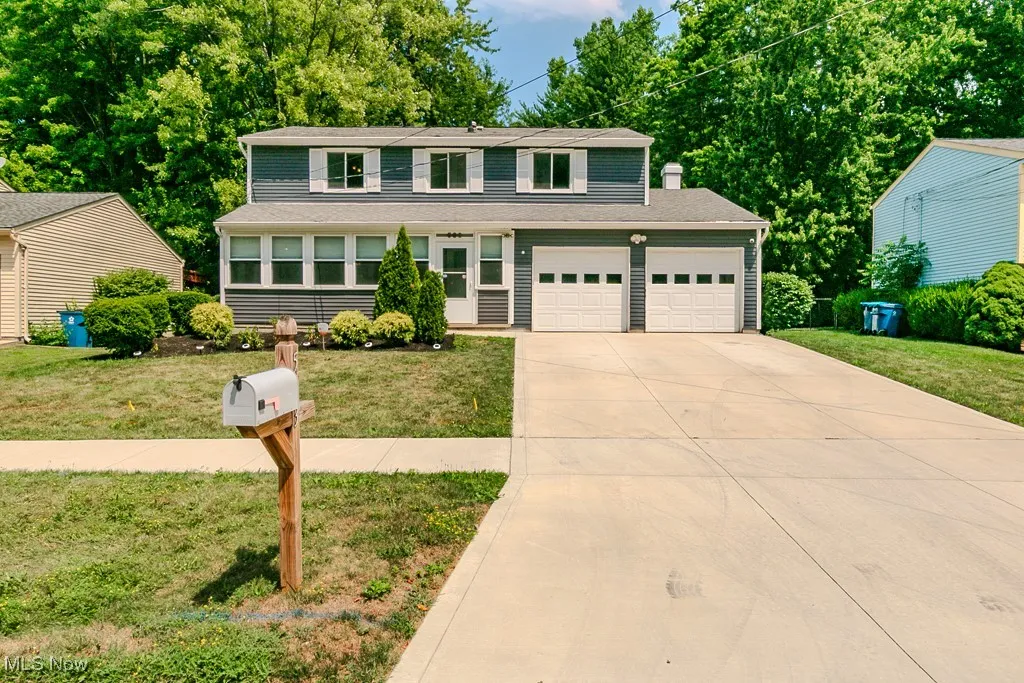 Traditional-style home featuring a front yard, concrete driveway, two car garage, and a sunroom