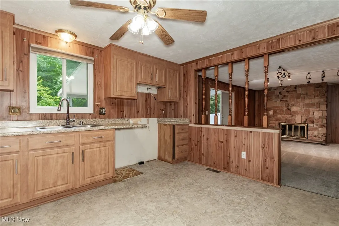 Kitchen and family room featuring wooden walls,  a ceiling fan and sliding glass door to back yard.
