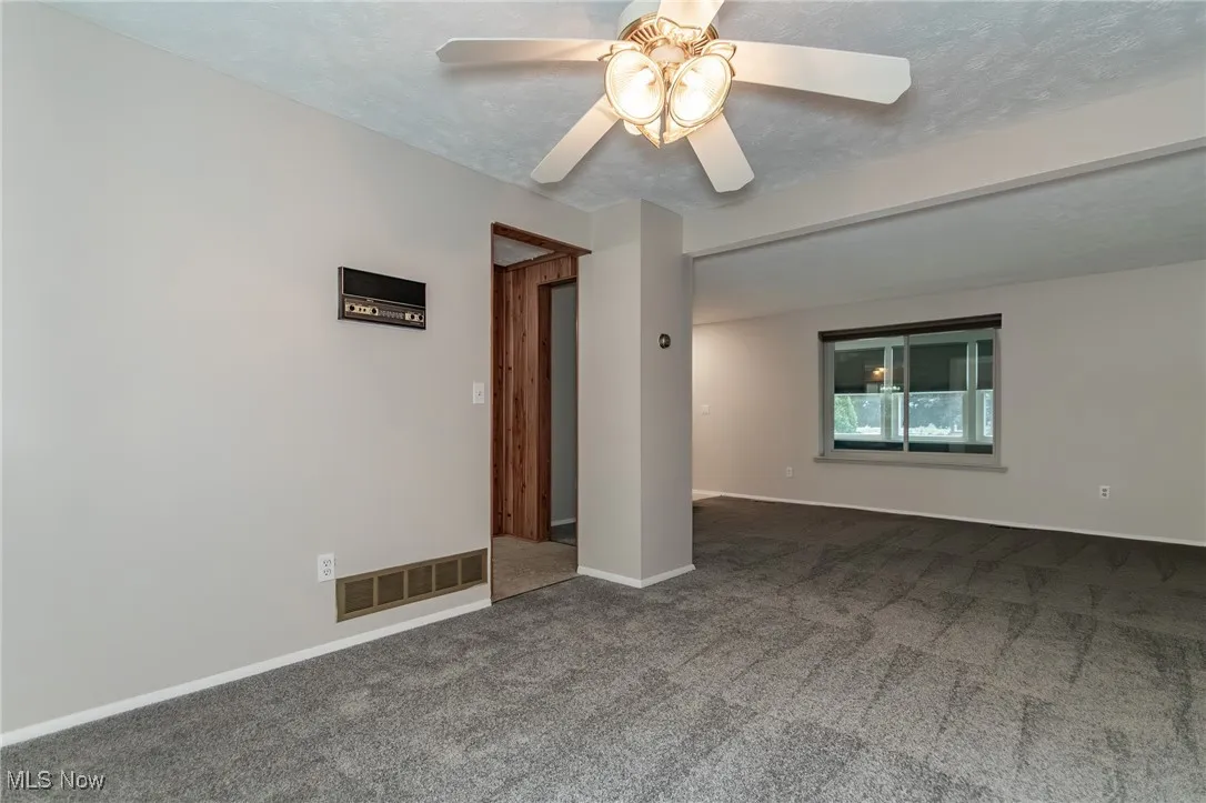 Carpeted dining room with a ceiling fan and a front living room