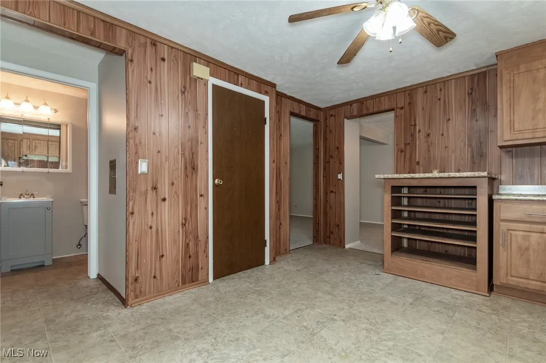 Kitchen with wood walls, a ceiling fan, and first floor bathroom