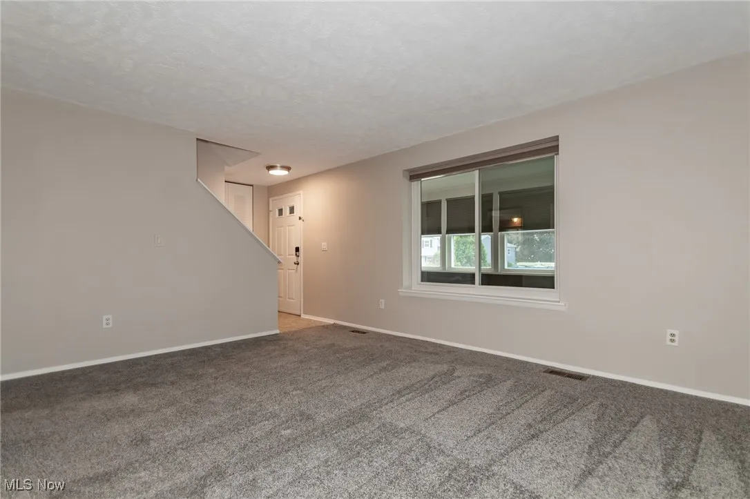 Unfurnished room featuring carpet and view of the front door.